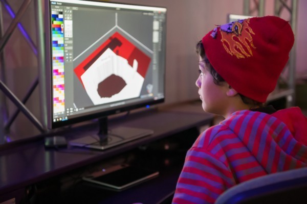 Boy looking at a computer screen building a room with MagicaVoxel