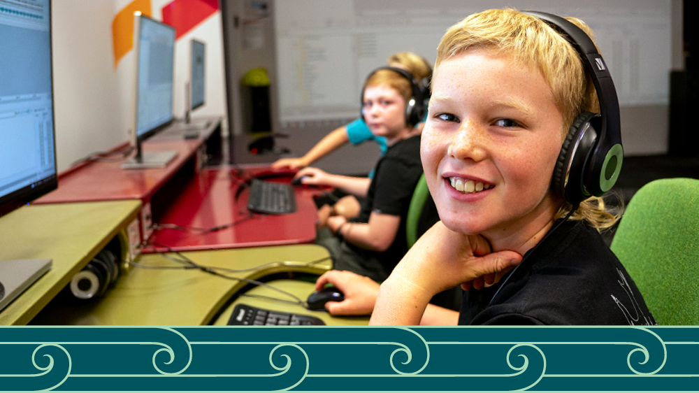 A child using a computer in the MediaLab, smiling.