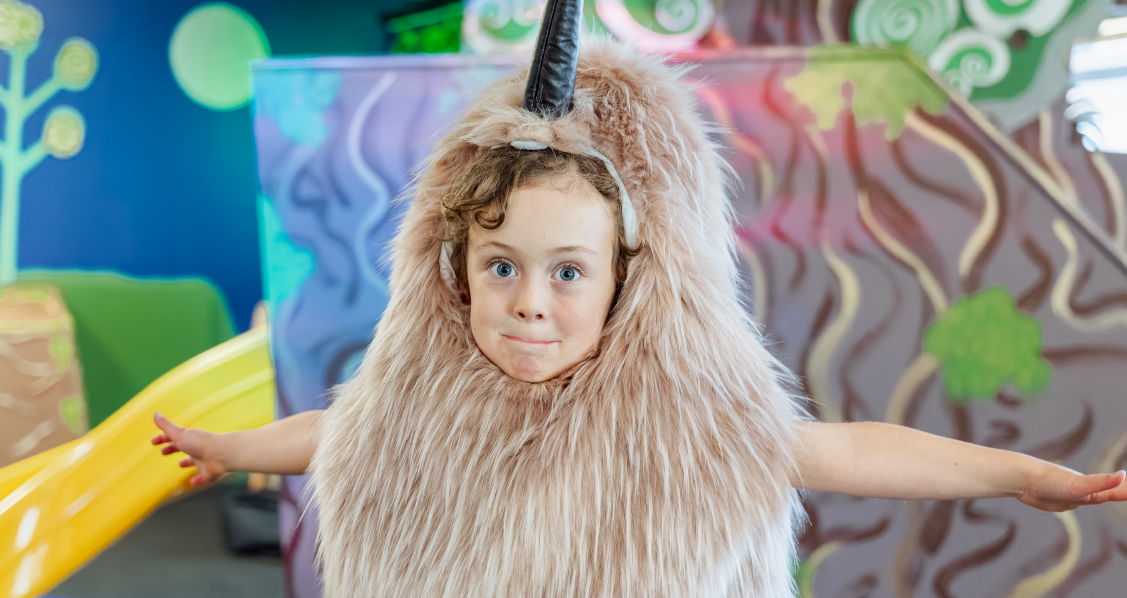 A child in a kiwi costume stands in front of a slide